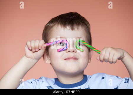 Eine nette Junge hält zwei candy Sticks. Gestreifte Zuckerstange Stockfoto