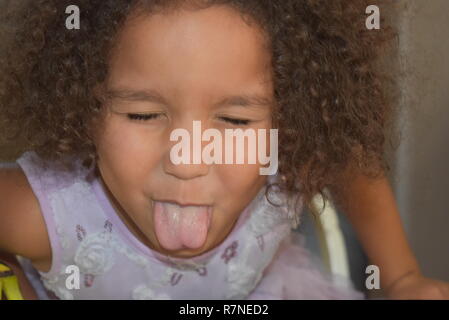 Kleines Mädchen mit herausgestreckter Zunge kleben Stockfoto