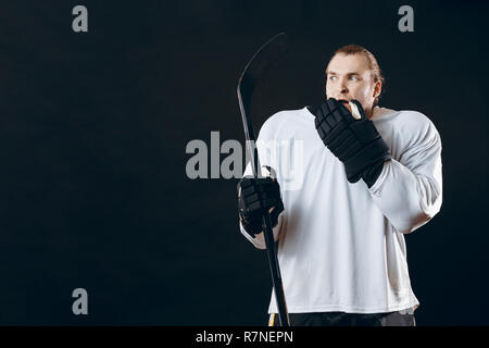 Hübscher junger Mann, Hockey Stick deckt den Mund mit der Hand drückt Angst Stockfoto