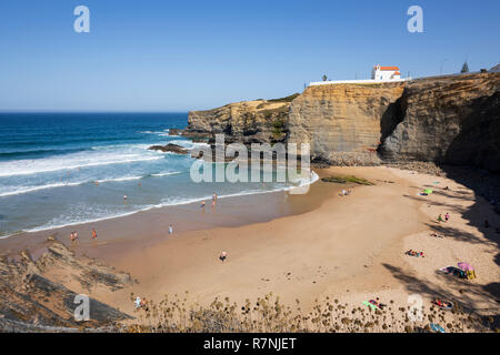 Klippe Kapelle von Igreja de Nossa Senhora do Mar mit Wellen des Atlantiks am Sandstrand in der Morgensonne brechen bei Zambujeira do Mar Stockfoto