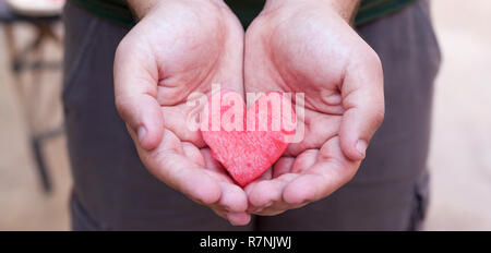Hände geben ein rotes Herz aus der Wassermelone. Gesundheit und Medizin Konzept Stockfoto