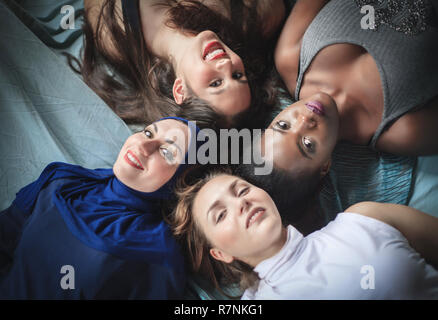 Vier Mädchen verschiedener Nationalitäten liegen, Studio gedreht. Positive Emotionen. Stockfoto