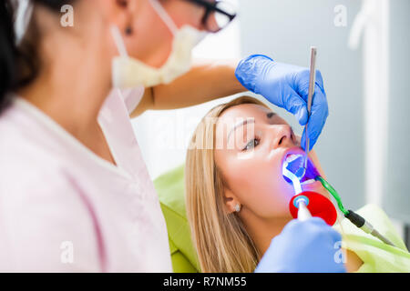 Junge Frau beim Zahnarzt. Zahnarzt besteht in der Reparatur der Zähne. Stockfoto