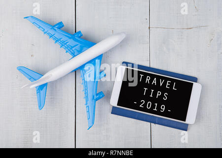 Adventure Time-plane, Reisepass und Smartphone mit Text' Reisetipps 2019' auf weiße Holztisch Stockfoto