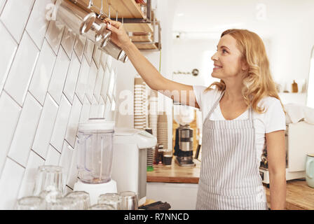 Schöne Frau Anordnen von cups im Cafe Stockfoto