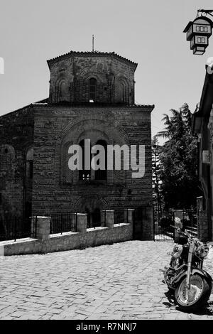 Monochrome Ansicht der kontrastierenden mittelalterliche Kirche Hagia Sophia, Ohrid, Mazedonien und glänzenden neuen Harley Davison Motorrad vor es in der Straße mit Kopfsteinpflaster Stockfoto