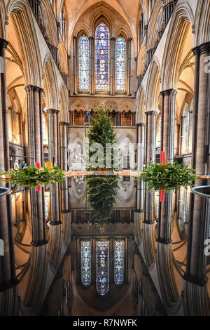 Kirchliche der Kathedrale von Salisbury joiner, Richard Pike schmückt die 34 ft Fichte Weihnachtsbaum, an der Longleat Immobilien gefällt, da die endgültige Garnituren, einschließlich 1000 LED-Leuchten, Glas Kugeln und Eis Tröpfchen, die auf dem Baum, der vor dem Westen Fenster steht platziert sind. Stockfoto