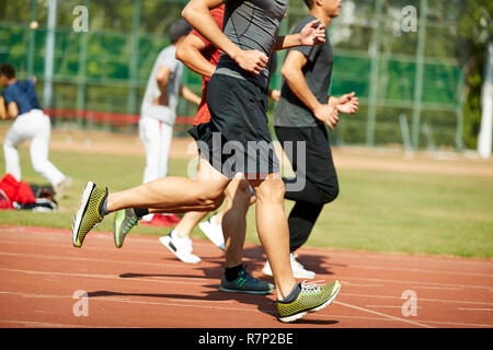 Vier jungen asiatischen Leichtathleten racing gegeneinander konkurrieren. Stockfoto