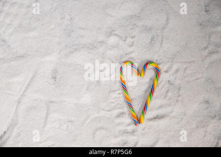 Zuckerstangen in Form eines Herzens gegen weiße Hintergrund angeordnet valentine Konzept zu vermitteln. bunten Lutscher. Candy valentines Herz. bunte Weihnachten Zuckerstangen. Grußkarte. Platz kopieren Stockfoto