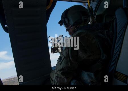 Eine Tür gunner auf ein UH-60 Black Hawk Hubschrauber aus der im Aviation Brigade, Oklahoma National Guard, Durchkämmt der Erde unten während der gemeinsamen Ausbildung bei Falcon Bombardierungstrecke, Fort Sill, Okla., Jan. 22, 2017. Der 137 Air Support Element aus der 137 Special Operations Wing, Oklahoma City, eine gemeinsame Veranstaltung mit der 123 Spezielle Taktiken Squadron, Kentucky Air National Guard, Air Force Reserve F-16 von der 301 Fighter Wing und T-38 s von der 88th Fighter Training Squadron, Sheppard Air Force Base, März 20-23, 2017 abgestimmt. Stockfoto