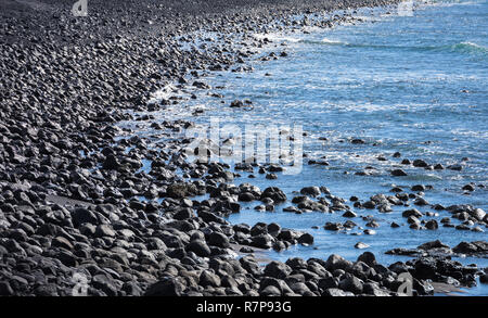 Schwarzer Stein Strand und Meer. Stockfoto
