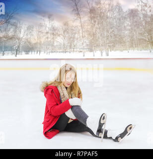 Junge Frau fiel auf der Eisbahn im Freien Stockfoto