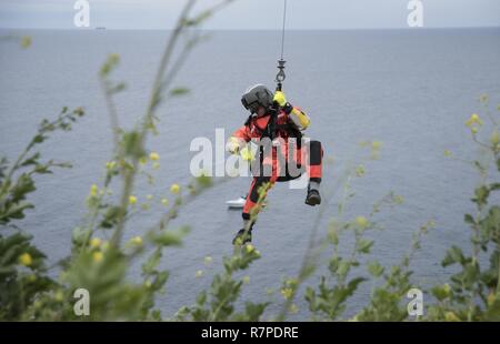 Eine Rettungsschwimmerin zugeordnet Küstenwache Forward Operating Base Point Mugu ist von einem MH-65 Dolphin Hubschrauber auf einer Klippe während rescue Training am Point Vicente Leuchtturm am 21. März 2017 verringert. Die Ausbildung trägt dazu bei, dass Flugzeugbesatzungen im Falle einer realen Welt Klippe retten beherrschen. Stockfoto