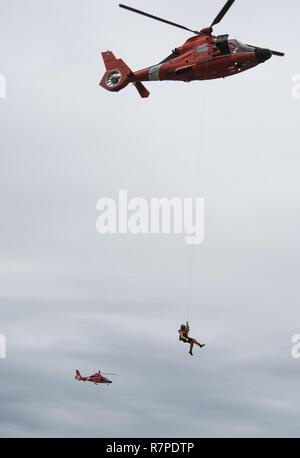 Eine Rettungsschwimmerin zugeordnet Küstenwache Forward Operating Base Point Mugu ist von einem MH-65 Dolphin Hubschrauber auf einer Klippe während rescue Training am Point Vicente Leuchtturm am 21. März 2017 verringert. Die Ausbildung trägt dazu bei, dass Flugzeugbesatzungen im Falle einer realen Welt Klippe retten beherrschen. Stockfoto