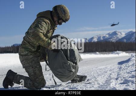 Us Air Force Senior Airman Sam Gomez, ein Tactical Air Control party Spezialist, auf den 3. Air Support Operations Squadron zugeordnet, erholt sich sein Fallschirm Packung nach dem Springen von einem UH-60 Black Hawk Hubschrauber Malemute Drop Zone auf einer gemeinsamen Basis Elmendorf-Richardson, Alaska, 22. März 2017. 1. Der Alaska Army National Guard Battalion, 207 Aviation Regiment zur Verfügung UH-60 Black Hawk Hubschraubern der Sprung zur Schulung. Stockfoto