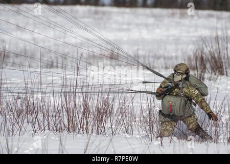 Us Air Force Master Sgt. Logan Englisch, ein Tactical Air Control party Spezialist, auf den 3. Air Support Operations Squadron zugeordnet, erholt sich sein Fallschirm, nach der Landung auf malemute Drop Zone während Hubschrauber springen Ausbildung bei Joint Base Elmendorf-Richardson, Alaska, 22. März 2017. 1. Der Alaska Army National Guard Battalion, 207 Aviation Regiment zur Verfügung UH-60 Black Hawk Hubschraubern der Sprung zur Schulung. Stockfoto