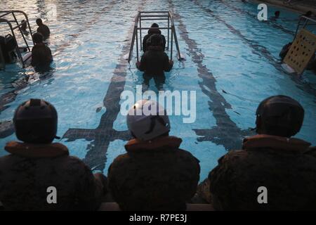 Marinesoldaten und Matrosen zu Bravo Unternehmen zugewiesen sind, 1.BATAILLON, 3. Marine Regiment, Durchführung Flachwasser Egress Training an der Basis Pool, an Bord der Marine Corps Base Hawaii, 23. März 2017. Das Ziel dieses Trainings ist es, service Mitglieder für einen Notausstieg im Falle einer Bruchlandung über Wasser vorzubereiten. Stockfoto