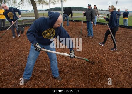 OAK Harbor, Washington (23. März 2017) Naval Aircrewman Mechanische 1. Klasse Alex Michelen der Patrol Squadron (VP) 40 rechen Holz Chips auf einem Spielplatz während einer Community service Veranstaltung im Windjammer Park in Oak Harbor, Washington Segler aus der VP-40 Chaos Leiter und die erste Klasse der Petty Officer Association gemeinsam Spielgeräte als Teil einer CPO 365 Team aufzubauen. CPO 365 ist ein das ganze Jahr über Programm, das first class Unteroffiziere Leiter zu werden. Stockfoto