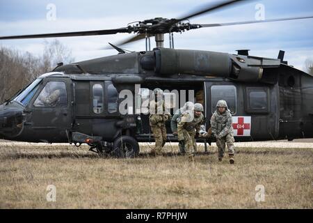 Us-Soldaten, die öffentliche Gesundheit Befehl Europa zugeordnet, sammeln eine simulierte kausalität von einem UH-60 Blackhawk, durch US-Soldaten betrieben, bis 12 Combat Aviation Brigade zugeordnet, da sie verschiedene Arten von medizinischen Evakuierungen durchzuführen, bei der 7th Army Training Befehl Grafenwöhr Training Area, Deutschland, 21. März 2017. Die Soldaten durchgeführt, MEDEVAC-Ausbildung die Möglichkeit, mit Flug Mediziner zu Team Patienten zum sicheren Transport von einem Hubschrauber zu entwickeln. Stockfoto