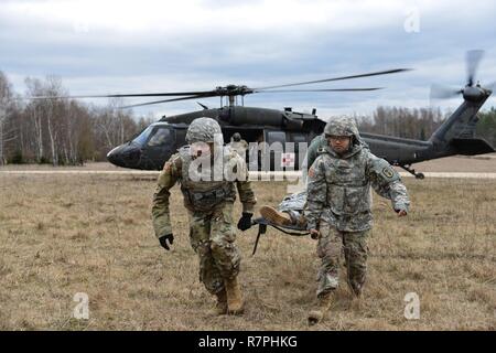 Us-Soldaten, die öffentliche Gesundheit Befehl Europa zugeordnet, sammeln eine simulierte kausalität von einem UH-60 Blackhawk, durch US-Soldaten betrieben, bis 12 Combat Aviation Brigade zugeordnet, da sie verschiedene Arten von medizinischen Evakuierungen durchzuführen, bei der 7th Army Training Befehl Grafenwöhr Training Area, Deutschland, 21. März 2017. Die Soldaten durchgeführt, MEDEVAC-Ausbildung die Möglichkeit, mit Flug Mediziner zu Team Patienten zum sicheren Transport von einem Hubschrauber zu entwickeln. Stockfoto