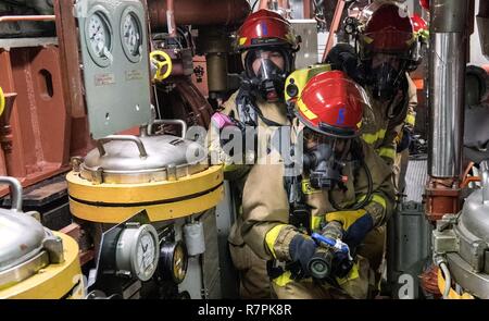 7. US-Flotte von Operationen (27. März 2017) Segler Mann einen Wasserschlauch in einem Hauptraum brandschutzübung an Bord Ticonderoga-Klasse geführte-missile Cruiser USS Lake Champlain (CG57). Lake Champlain ist in regelmäßigen Western Pacific Bereitstellung mit der Carl Vinson Carrier Strike Group als Teil der US-Pazifikflotte-Initiative die Befehls- und Steuerfunktionen der USA 3 Flotte in der Indo-Asia zu verlängern - Pazifik Region. Navy Flugzeugträger Streik Gruppen haben die Indo-Asia - Pazifik regelmäßig und routinemäßig Seit mehr als 70 Jahren patrouillierte. Stockfoto