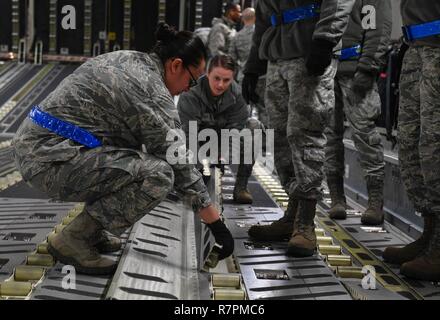 Staff Sgt. Jacquelyn Alvarez, Antenne Anschluss 721st Squadron NCO verantwortlich für die Einheit Learning Center, hilft ein Student flip Walzen über innerhalb eines C-17 Globemaster III vor dem Laden Ladung auf das Flugzeug auf der Air Base Ramstein, Deutschland, 21. März 2017. Die Einheit Learning Center bietet neue Flieger die Ausbildung für Sie Ihre Upgrade Training für den Personenverkehr, Luftfracht, und Ramp Services. Stockfoto