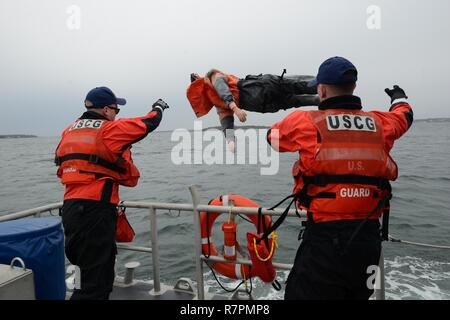 Zwei Seeleuten werfen Oscar, die Mannequin, in das Wasser in der Potter's Cove, Rhode Island am Freitag, März 24, 2017. Mannschaften von Coast Guard Station Castle Hill durchgeführt Boot Ausbildung, um ihre Rettung Fähigkeiten auf dem Laufenden zu halten. Stockfoto