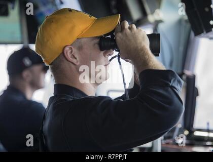 NDIAN OCEAN (27. März 2017), der Stern zog Foard, von Annapolis, MD., Scans der Horizont beim Stehen Offizier des Decks auf der Brücke der Amphibisches Schiff USS Makin Island (LHD8). Makin Island, das Flaggschiff der Makin Island amphibischen bereit, mit der begonnen 11 Marine Expeditionary Unit, arbeitet in der Indo-Asia-pazifischen Region amphibische Fähigkeit mit regionalen Partnern zu verbessern und als gebrauchsfertige Response Force für jede Art der Kontingenz zu dienen. Stockfoto