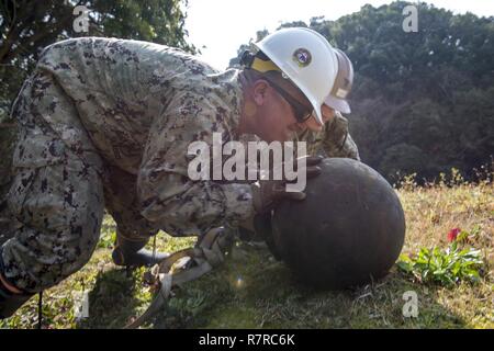 SASEBO, Japan (30. März 2017) Chief Utilitiesman Georgios Georgiadis und Builder 2. Klasse Jorge Aviles, sowohl zu Naval Mobile Konstruktion Bataillon 5 zugewiesen, drücken Sie einen Grabstein auf einem Hügel als Teil der Wiederherstellung der gefallenen Grabsteine aus der Umgebung auf Hario Shima Ordnance Facility onboard KFBS März 30, 2017. Die Grabsteine wurden zurückgewonnen und in einer stabilen Position zurücksetzen. Stockfoto