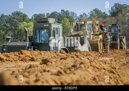 US Army Staff Sgt Edwin Williams, South Carolina Army National Guard, 218. Führung Regiment Ausbilder, bietet Beratung und Richtung Soldaten 621B motorisierte Spachtel und D7R Planierraupe, schnell ein 6-Fuß mit einer Push-Assist-Technik im Rahmen des Studiengangs horizontale Bau Ingenieur Umgliederung im McCrady Training Center, Eastover, South Carolina, 2. April 2017 Graben in Betrieb.  Soldaten, die derzeit in der Zweiphasen-Kurs eingeschrieben kamen aus Puerto Rico, Georgia, North Carolina.  Die vier Wochen intensives Training begann mit kleineren Stücken Ausrüstu Stockfoto