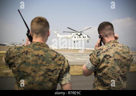 Us Marine Corps Lance Cpl. Daniel McGinness, gelassen und US Marine Corps Cpl. Stephen Wellman, rechts, Fluglotsen mit Sitz und Hauptverwaltung Squadron, Reiseführer Japan Maritime Verteidigung-kraft Hubschrauber Piloten auf einer dafür vorgesehenen Landestelle während eines Cross-Training bei Marine Corps Air Station Iwakuni, Japan, 30. März 2017. Die Marines nahmen an einer simulierten, Bewaffnung und Tankstellen, wo Sie mit JMSDF Hubschrauberpiloten mitgeteilt strenge Landungen auf einen Hubschrauberlandeplatz, der als expeditionary Landebahn gehandelt. Stockfoto