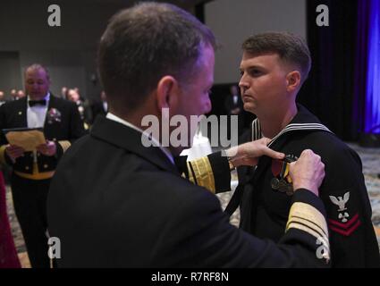 JEKYLL Island, Ga (April. 1, 2017) Vice Adm. Joseph Tofalo, Commander, Submarine Kräfte, Stifte einen eingetragenen U-Boot-Krieg Qualifikation Gerät auf der Machinist Mate 2. Klasse Seth's Dobson einheitliche an der Naval Submarine Base der Kings Bay 117 U-Boot Geburtstag Ball an der Jekyll Island Convention Center. Stockfoto