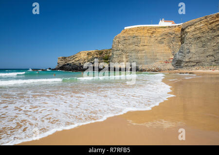 Klippe Kapelle von Igreja de Nossa Senhora do Mar mit Wellen des Atlantiks am Sandstrand in der Morgensonne brechen bei Zambujeira do Mar Stockfoto