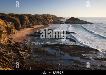 Praia dos Alteirinhos und Blick entlang der zerklüfteten Atlantikküste bei Sonnenuntergang, bei Zambujeira do Mar, Alentejo, Portugal, Europa Stockfoto