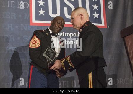 Kommandant des Marine Corps Gen. Robert B. Neller präsentiert ein USO besondere Grüße an Sergeant Major des Marine Corps Sgt. Maj. Ronald L. Grün an der USO 35th jährliche Preise Abendessen im Crystal Gateway Marriott Hotel, Arlington, Virginia, 21. März 2017. Grün war die Auszeichnung im Namen aller Marine Corps Senior Berater angeworben und Marine Corps Familien vorgestellt. Stockfoto