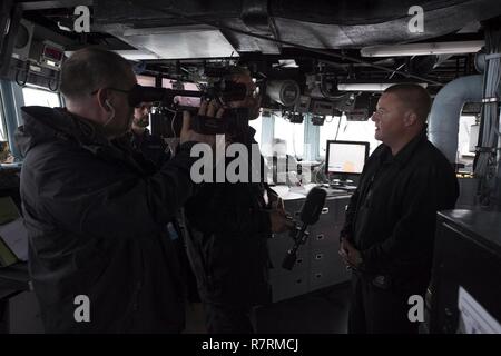 CAPE WRATH, Schottland - (April 3, 2017) - Cmdr. Peter Halvorsen, kommandierender Offizier, USS Carney (DDG64), führt eine simulierte Interview mit einer Übung media Crew während der Übung gemeinsame Krieger 17-1 April 3, 2017. Carney, einem der Arleigh-Burke-Klasse geführte-missile Destroyer, Vorwärts - Rota, Spanien bereitgestellt werden, ist die Durchführung der dritten Patrouille in den USA 6 Flotte Bereich der Maßnahmen zur Unterstützung der US-amerikanischen nationalen Sicherheitsinteressen in Europa. Stockfoto