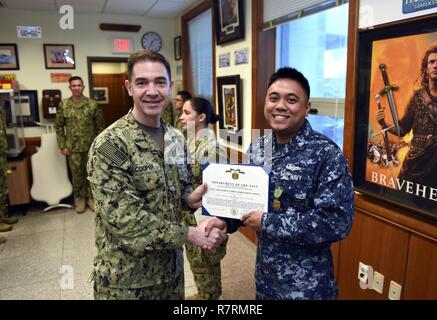 BUSAN, Republik Korea (6. April 2017) hinten Adm. Brad Cooper, Commander, U.S. Naval Forces Korea (CNFK) Auszeichnungen Information Systems Techniker 2. Klasse Karl Lance Carbonel ein Navy und Marine Corps Leistung Medaille während einer Auszeichnungen bei Viertel an CNFK Hauptquartier. CNFK ist Vertreter der U.S. Navy in der ROK, der Leitung und der Kompetenz in der Marine Fragen der institutionellen und operativen Wirksamkeit zwischen den beiden Marinen zu verbessern und der kollektiven Sicherheit Bemühungen in Korea und der Region zu stärken. Stockfoto