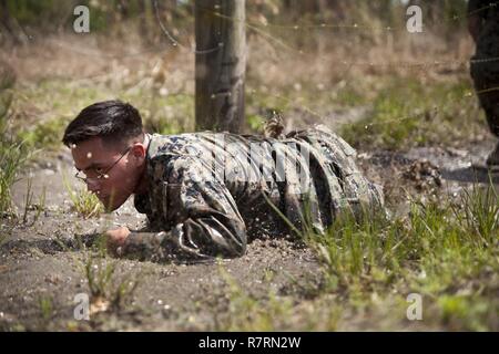 Ein US-Marine zu Masse Schule (GSS), Marine Corps Combat Service Support Schulen zugewiesen, kriecht durch den Schlamm während einem Dauerlauf im Camp Johnson, N.C., 29. März 2017. Die Marines der GSS lief an drei verschiedenen Stationen, die auf Hindernisse oder Buddy bestand schleppt und Feuerwehrmann trägt zur Bekämpfung Klimaanlage und Zusammenhalt zu gewährleisten. Stockfoto