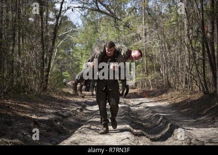 Ein US-Marine zu Masse Schule (GSS), Marine Corps Combat Service Support Schulen zugewiesen, Feuerwehrmann trägt eine Marine während einem Dauerlauf im Camp Johnson, N.C., 29. März 2017. Die Marines der GSS lief an drei verschiedenen Stationen, die auf Hindernisse oder Buddy bestand schleppt und Feuerwehrmann trägt zur Bekämpfung Klimaanlage und Zusammenhalt zu gewährleisten. Stockfoto