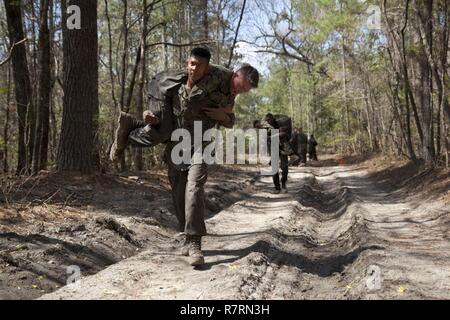 Ein US-Marine zu Masse Schule (GSS), Marine Corps Combat Service Support Schulen zugewiesen, Feuerwehrmann trägt eine Marine während einem Dauerlauf im Camp Johnson, N.C., 29. März 2017. Die Marines der GSS lief an drei verschiedenen Stationen, die auf Hindernisse oder Buddy bestand schleppt und Feuerwehrmann trägt zur Bekämpfung Klimaanlage und Zusammenhalt zu gewährleisten. Stockfoto