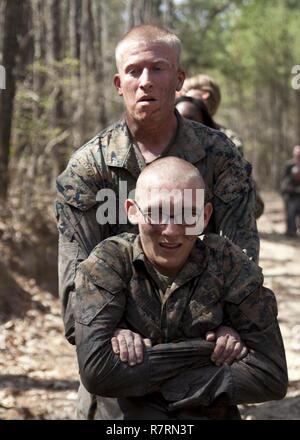 Ein US-Marine zu Masse Schule (GSS), Marine Corps Combat Service Support Schulen zugewiesen, Buddy zieht ein Marine während einem Dauerlauf im Camp Johnson, N.C., 29. März 2017. Die Marines der GSS lief an drei verschiedenen Stationen, die auf Hindernisse oder Buddy bestand schleppt und Feuerwehrmann trägt zur Bekämpfung Klimaanlage und Zusammenhalt zu gewährleisten. Stockfoto