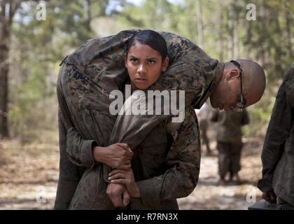 Ein US-Marine zu Masse Schule (GSS), Marine Corps Combat Service Support Schulen zugewiesen, Feuerwehrmann trägt eine Marine während einem Dauerlauf im Camp Johnson, N.C., 29. März 2017. Die Marines der GSS lief an drei verschiedenen Stationen, die auf Hindernisse oder Buddy bestand schleppt und Feuerwehrmann trägt zur Bekämpfung Klimaanlage und Zusammenhalt zu gewährleisten. Stockfoto