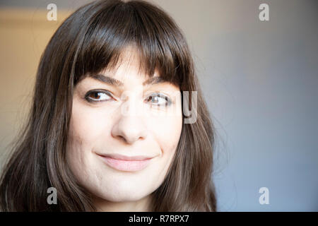 Junge Frau Nahaufnahme Porträt. Kaukasische mit braunen langen Haaren und Pony. Lächelnd Ausdruck der Rechten. Stockfoto