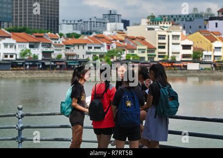 Singaporean Mädchen durch den Singapore River, im Hintergrund die Restaurants und Bars von Boat Quay, in umgebauten Lagerhallen oder godowns entfernt Stockfoto