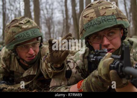 Eine britische Armee cadet Truppführer leitet ein Gefährte Cadet, wo sich die 2017 Sandhurst militärischen Fähigkeiten Konkurrenz an der United States Military Academy, West Point, New York, April 7, 2017. Während Sandhurst, 62 Mannschaften aus 12 internationalen Militärakademien, vier US-Akademien und acht ROTC Programme in 11 Fällen während einer 23-Meile Kurs teilgenommen. Stockfoto