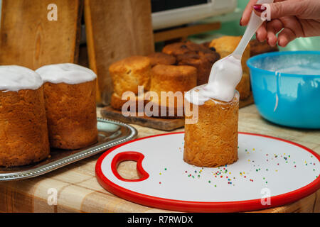 Die Frau ist mit einem süßen Glasur auf Ostern Kuchen. Stockfoto