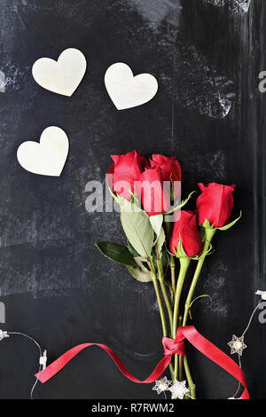 Blick von oben auf die wunderschöne langstielige Rosen für Valentines Tag gebunden mit einem roten Band mit Lichterketten und hölzerne Herz geformte Aussparungen. Stockfoto