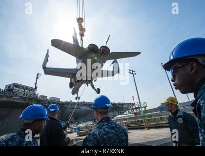 YOKOSUKA, Japan (5. April 2017) Segler durchführen Kran Operationen einen stillgelegten F/A-18C Super Hornet an Bord der Marine nur Weiterleitung bereitgestellten Flugzeugträger USS Ronald Reagan (CVN 76), für Flight Deck Bohrer. Ronald Reagan, das Flaggschiff der Carrier Strike Group 5, bietet eine Bekämpfung bereit, Kraft, schützt und verteidigt die kollektive maritime Interessen seiner Verbündeten und Partnern in der Indo-Asia-Pazifik-Region. Stockfoto