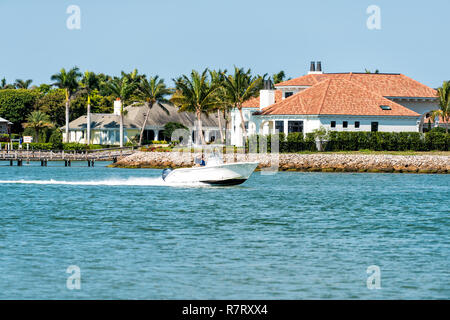 Neapel, USA - 30. April 2018: Nelson's Walk orange Haus Gebäude mit Wasser auf Dollar Bay, Palmen, blauer Himmel in Wohngemeinschaft, Leute auf r Stockfoto