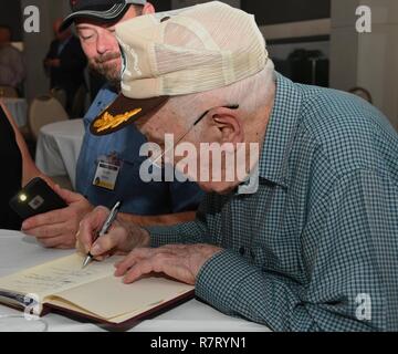 Ein 307Th Bomb Wing alumni Zeichen ein Buch über die Geschichte der 307th Bombardement einer Gruppe während eines Reunion icebreaker Veranstaltung im Shreveport Convention Center, Shreveport, La., 30. März 2017. Die 307Th BW gehostete ein Wiedersehen zum 75. Jahrestag der Einheit zu feiern und Alumni aus Kriege wie den Zweiten Weltkrieg, dem Koreakrieg, Vietnam und den Kalten Krieg. Stockfoto